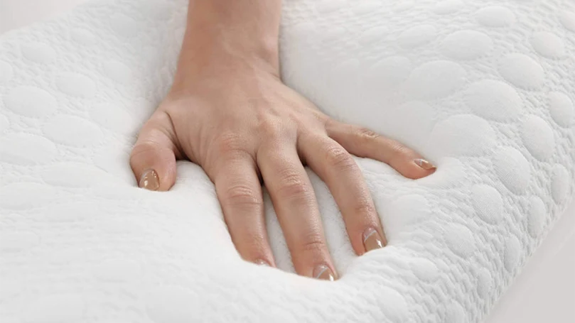 En kvindehånd, der trykker på en madras med memoryskum