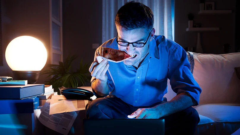 En mand arbejder på en bærbar computer sent om aftenen i mørket.