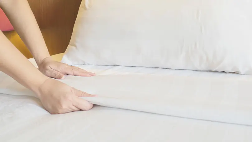 En kvinde tager rent sengetøj på