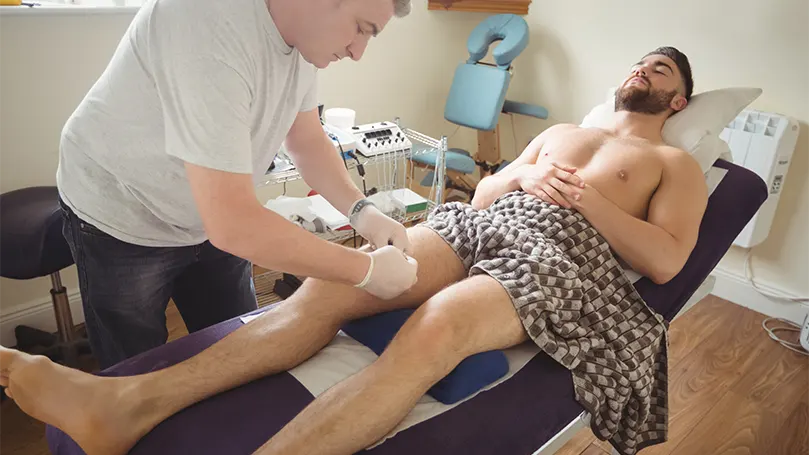 Et billede af en mand, der får massage af en fysioterapeut på en inclided-klinik.