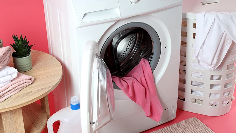 Et billede af sengetøj og tøj i en vaskemaskine.
