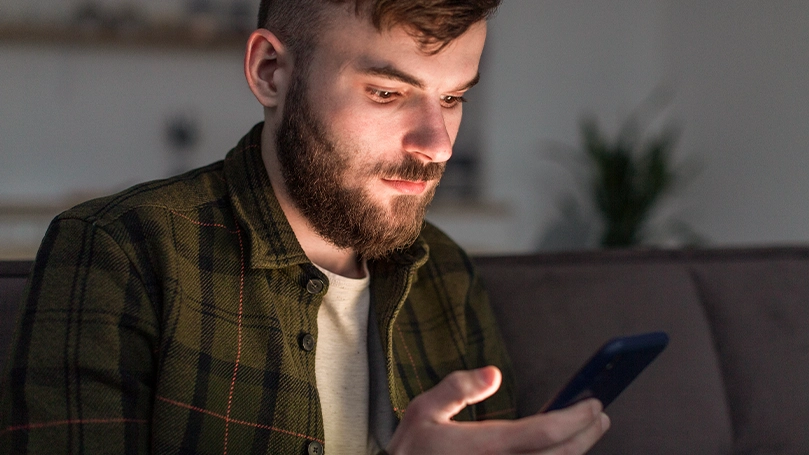 Et billede af en mand, der kigger på sin telefon inden sengetid.