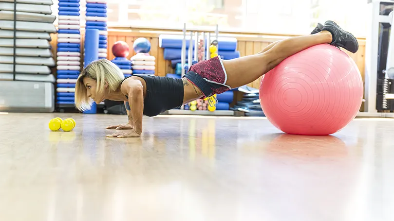 Et billede af en kvinde, der laver Decline pushups på en yogabold.