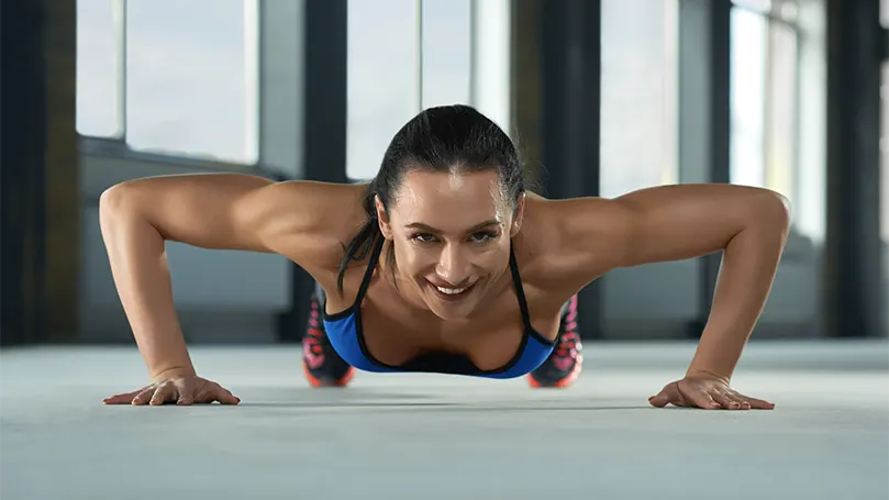 Et billede af en ung kvinde, der laver pushup.