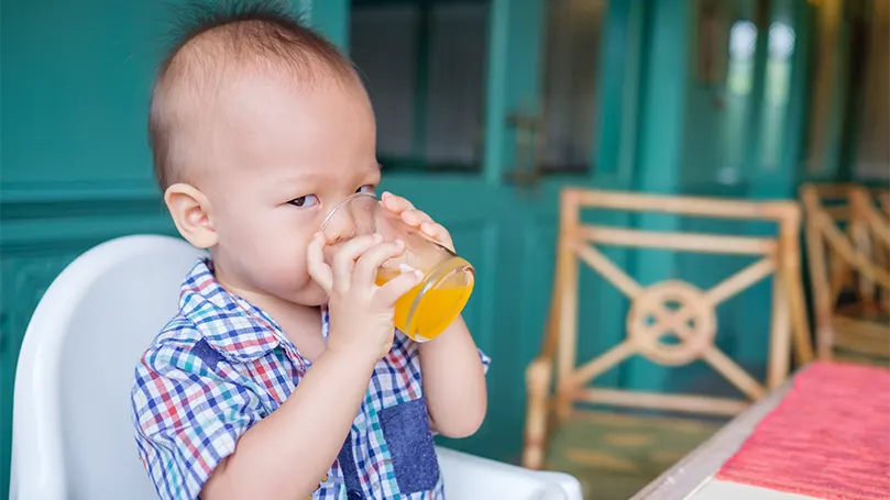 Et billede af en 18 måneder gammel baby, der drikker juice.