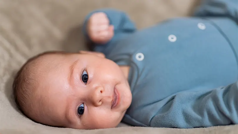 Et billede af en 2 måneder gammel baby, der ligger på ryggen.