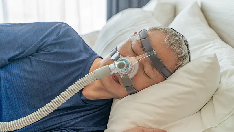 En ældre mand sover med CPAP-maske