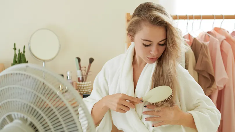 Et billede af en smuk kvinde foran en ventilator.