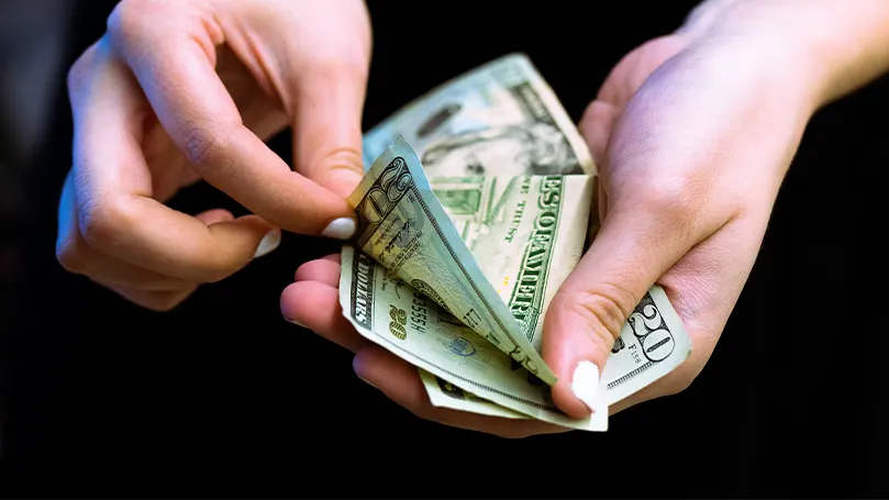 Et billede af en person, der tæller sine penge