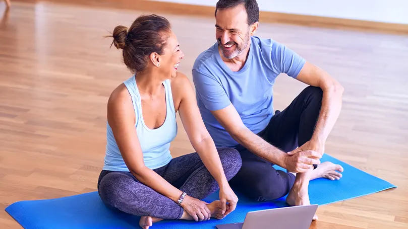 Et billede af to mennesker, der tager et hvil på en yogamåtte efter at have trænet og været aktive.