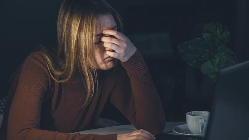 Et billede af en kvinde med angst om natten, der holder sit ansigt med hånden.