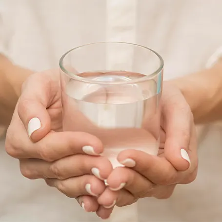 Et billede af en kvinde, der holder et glas vand.